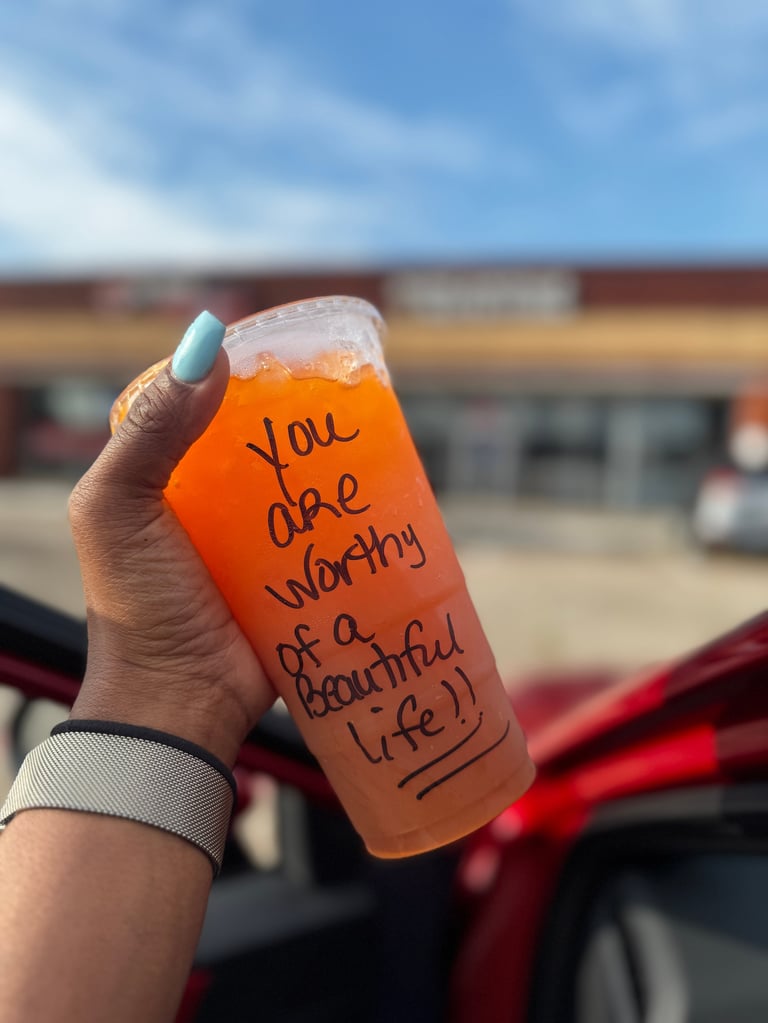Hand holding orange beverage with text reading you are worthy of a beautiful life